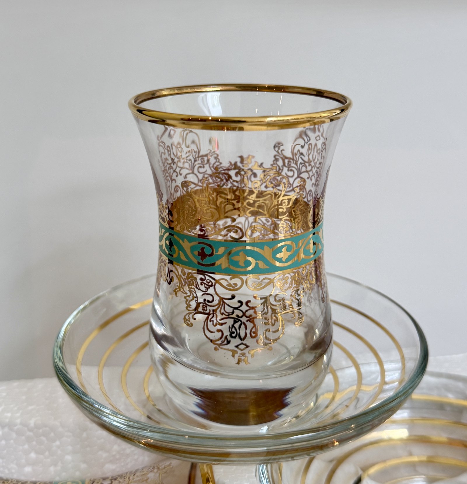 Un verre à thé turc et sa soucoupe, bande turquoise et arabesque dorée